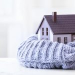 Figure of house and warm scarf on table. Concept of heating seas