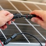 Close up of technician’s hands connecting mc4 connectors over the solar panel.